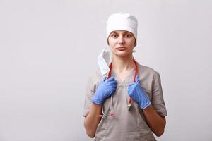 portrait de femme médecin en uniforme médical et masque retiré du visage. stéthoscope sur le cou. sur fond blanc. la santé et la médecine. concept de prévention des maladies. photo