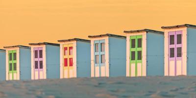 rangée de vieilles cabines de plage en bois pendant le coucher du soleil photo
