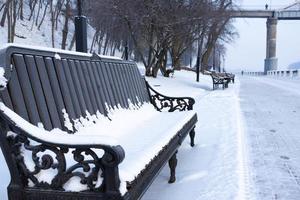 beaux bancs dans un parc couvert de neige. photo