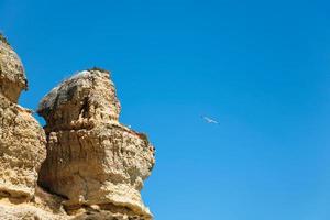 falaise de grès érodée et mouette dans le ciel bleu photo