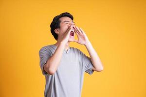 image d'un homme asiatique hurlant, isolé sur fond jaune photo
