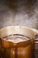 le café naturel et fraîchement torréfié est préparé dans un turc en métal au-dessus d'un feu. café chaud avec de la mousse. photo