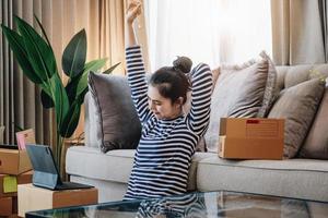 idée d'entreprise en ligne, belle fille à la maison vérifiant les produits commandés par les clients sur la tablette afin d'emballer les produits dans la boîte à colis pour la livraison aux clients. photo