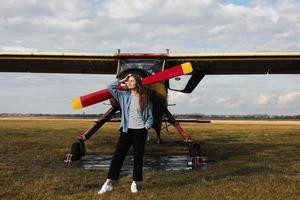 portrait de jeune femme près de l'avion rétro. terrain avec avion survolant. photo