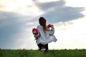 fille dans le champ de fleurs. une fille avec de la pivoine se promène dans le champ photo