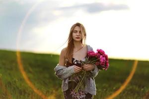 fille dans le champ de fleurs. portrait d'une jeune fille aux fleurs roses photo