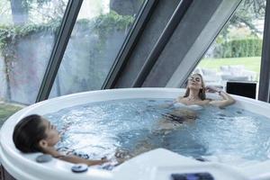 photo de deux jeunes femmes se relaxant dans un jacuzzi. amis ayant une journée au spa