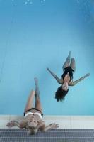 photo de recul de deux jeunes femmes se relaxant dans la piscine d'un spa