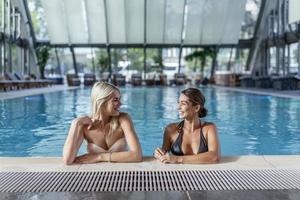 femmes amies boivent, cocktail mojito au bar de la piscine, portent un bikini hôtel de luxe près de la plage sur l'île tropicale se détendre. belles jeunes femmes s'amusant dans la piscine, buvant un cocktail, souriant. photo