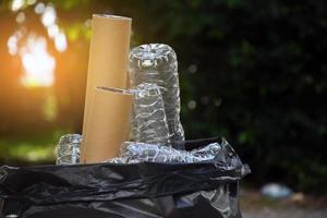 le propriétaire sépare les bouteilles, le papier, les cartons d'œufs et d'autres objets dans le sac en plastique noir devant la maison, concept pour réduire le réchauffement climatique, sauver notre monde, mise au point douce et sélective. photo