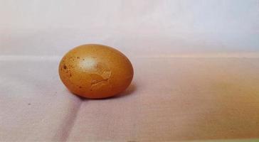c'est la photo d'un œuf fêlé, sur fond rose.