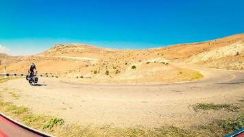 monter un jeune homme de race blanche à vélo avec un vélo de randonnée en montée sur une route déserte dans les montagnes du caucase. concept de réalisation, d'inspiration, de défi et de détermination photo