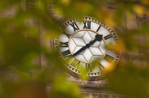 grande horloge antique à travers des feuilles d'érable photo