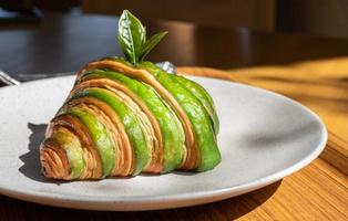 matcha ou croissant au thé vert servi avec assiette sur table en bois. le croissant est un pain français au beurre, feuilleté et en forme de croissant. photo