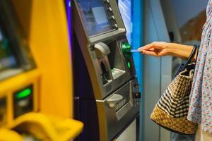 main de femme insérez une carte de crédit dans un guichet automatique. photo