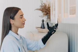 jolie fille handicapée ouvre le placard de la cuisine par un bras prothétique bionique. publicité de prothèse moderne photo