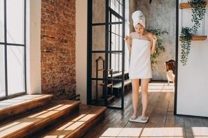 femme excitée debout sur une balance au sol, mesurant le poids après un régime, célébrant le succès de l'amincissement photo