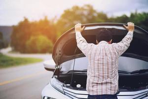 un jeune homme stressé ayant des problèmes avec son accident de salle des machines de voiture cassée par le stress à un moteur en panne attend de l'aide. photo