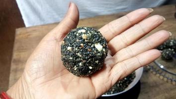 boules de graines de sésame noir - bonbon à base de sésame et de sucre de palme. boules de tilgul laddu ou til gul pour makar sankranti, boules de thala rôties. photo