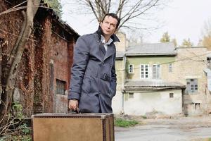 homme adulte moyen pensif avec valise à l'extérieur. photo