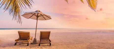 belle nature panoramique. coucher de soleil sur la plage tropicale comme paysage d'île d'été avec chaises parasol feuilles de palmier calme bord de mer, côte. bannière de destination panoramique de voyage de luxe pour des vacances ou des vacances photo
