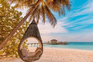 coucher de soleil sur la plage tropicale comme paysage d'été avec hamac de balançoire de palmier de plage de luxe, rivage de sable en bord de mer pour le paysage de plage au coucher du soleil. concept de vacances et de vacances d'été de paysage de plage tranquille