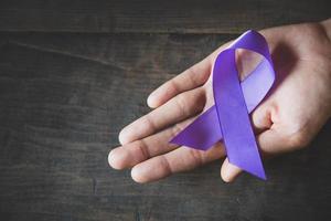 ruban violet dans une main de femme, concept de mois de sensibilisation à la violence domestique avec ruban de sensibilisation violet foncé. photo