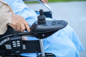 patiente asiatique âgée ou âgée vieille dame sur fauteuil roulant électrique avec télécommande à l'hôpital de soins infirmiers, concept médical solide et sain photo