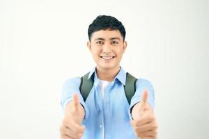 jeune étudiant homme avec sac à dos tenant deux mains avec le pouce vers le haut geste sur fond blanc photo