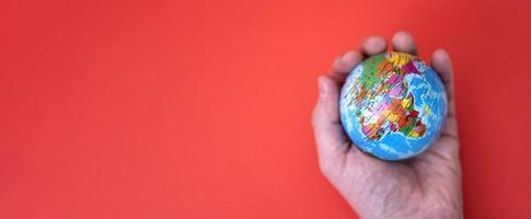 globe à la main sur fond rouge et papier avec un espace pour le texte. photo