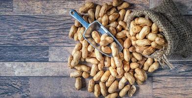 cacahuètes ou noix séchées dans des sacs bruns versés sur fond de bois photo