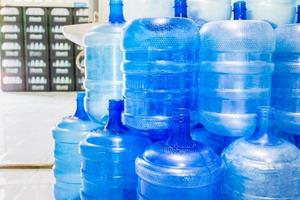 des bouteilles en plastique bleu ou des gallons bleus d'eau potable sont empilés dans l'usine d'eau potable pour faire circuler l'eau potable. concept d'entreprise d'usine d'eau photo