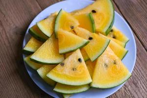 tranches de pastèque sucrées morceaux de pastèque fraîche fruits d'été tropicaux, tranche de pastèque jaune sur assiette et fond en bois photo