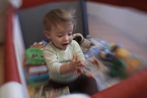 mignon petit bébé jouant dans un lit mobile photo