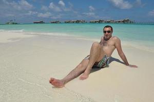 jeune homme s'amuser et se détendre sur la plage photo