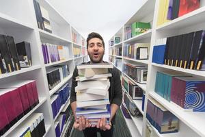 étudiant tenant beaucoup de livres dans la bibliothèque de l'école photo