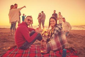 couple profitant avec des amis au coucher du soleil sur la plage photo