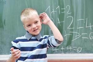 heureux jeune garçon aux cours de mathématiques de première année photo