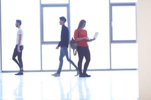 étudiante debout avec un ordinateur portable, groupe de personnes passant par photo