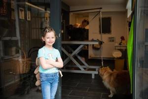 petite fille mignonne debout devant un salon de beauté pour animaux photo