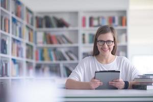 Étudiante étudie à la bibliothèque de l'école, à l'aide d'une tablette photo