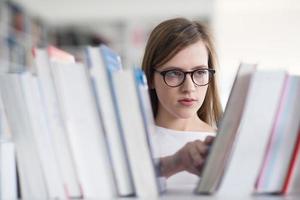 portrait d'une étudiante célèbre qui sélectionne un livre à lire dans la bibliothèque photo