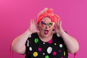 femme de taille plus heureuse portant des lunettes souriant à la caméra debout sur fond rose. joyeuse femme millénaire en lunettes posant en studio. photo