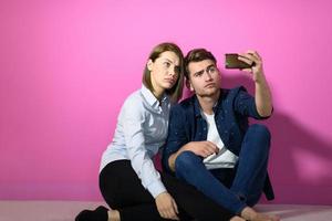 un jeune couple heureux assis sur le sol dans la maison et faisant du selfie photo