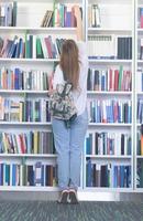 étudiante célèbre en sélectionnant un livre à lire dans la bibliothèque photo