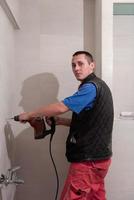 ouvrier du bâtiment percer des trous dans la salle de bain photo