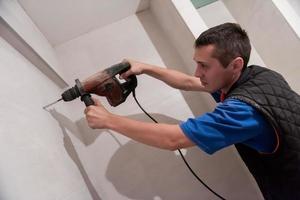 ouvrier du bâtiment percer des trous dans la salle de bain photo