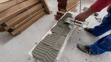 travailleur installant les carreaux en céramique effet bois sur le sol photo