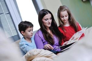 jeune maman joue avec ses enfants à la maison et lit un livre photo