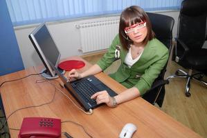 souriante jeune femme d'affaires travaillant sur un ordinateur portable au bureau. photo